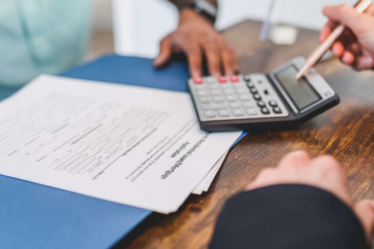 Calculator beside a mortgage application form on a wooden table.