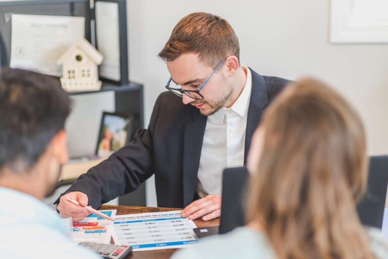 Three people reviewing a printed mortgage chart at a desk.